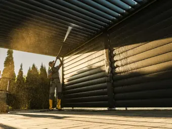 pán co pomocí hadice čistí střechu svoji pergoly neboli garáže